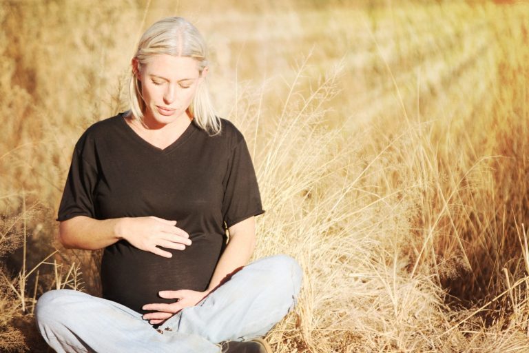 Mujer embarazada sentada en un campo